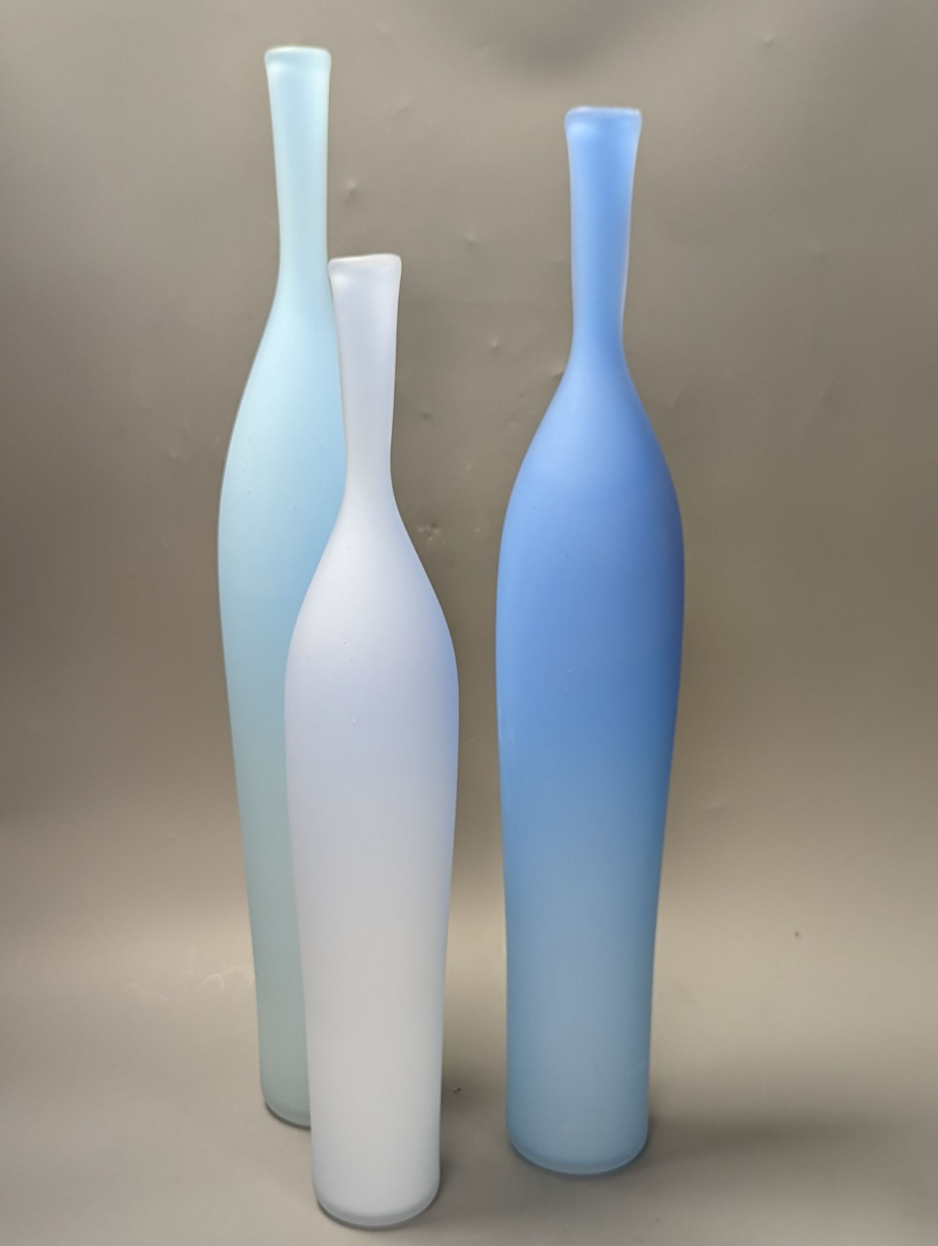 Three contemporary blue glass bottle vases, tallest 55cms high.